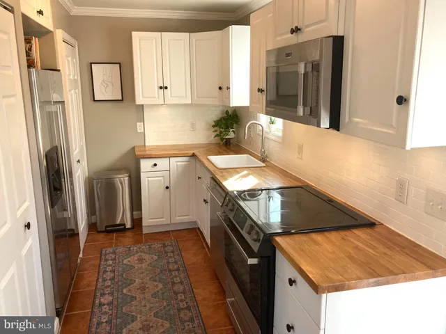 a kitchen with stainless steel appliances granite countertop a refrigerator a stove and a sink with wooden floor