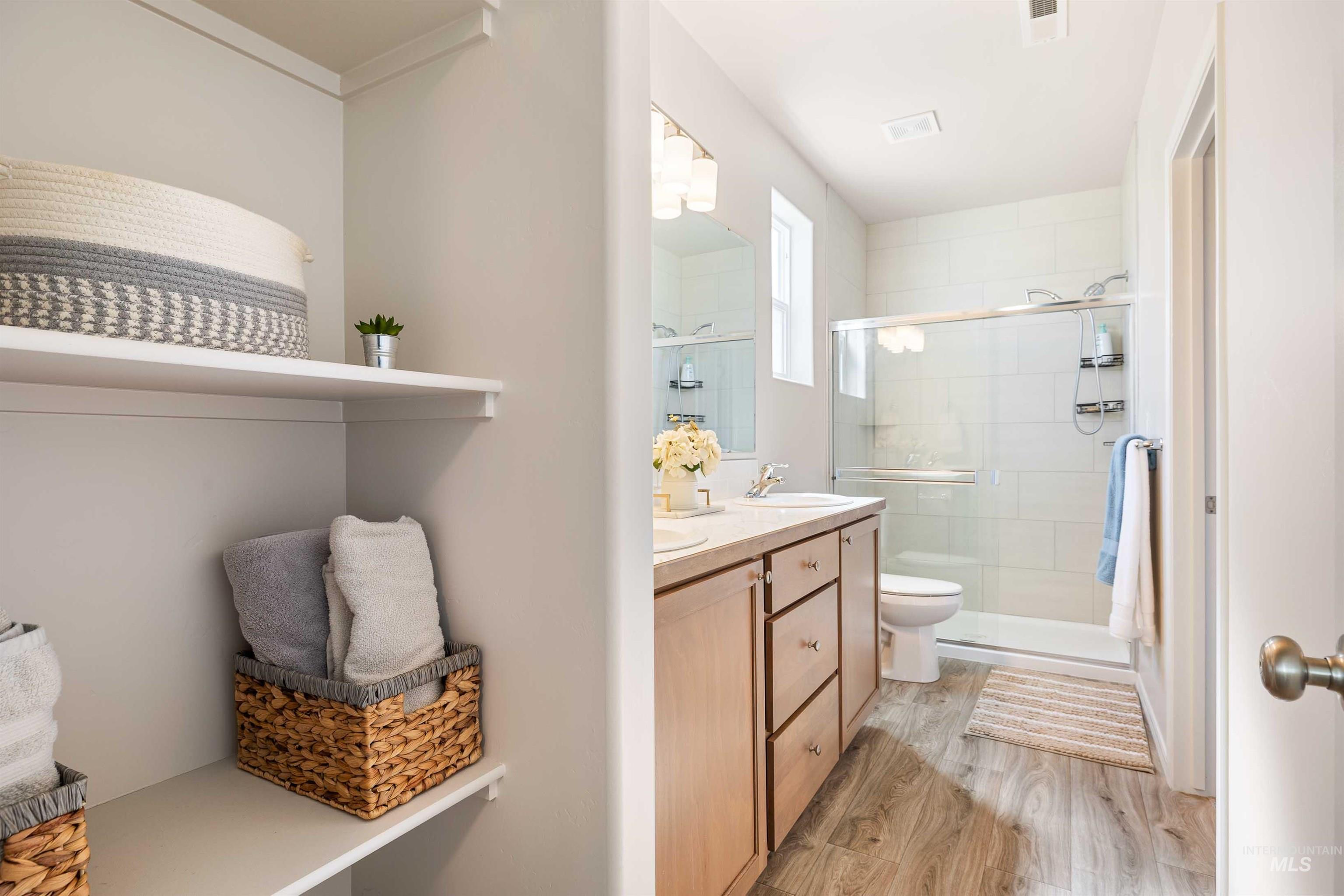 1603 Kenyon Mdw Street Twin Falls, ID 83301 - Photo 12 of 34 Full bath with a stall shower, light wood-style floors, double vanity, and crown molding