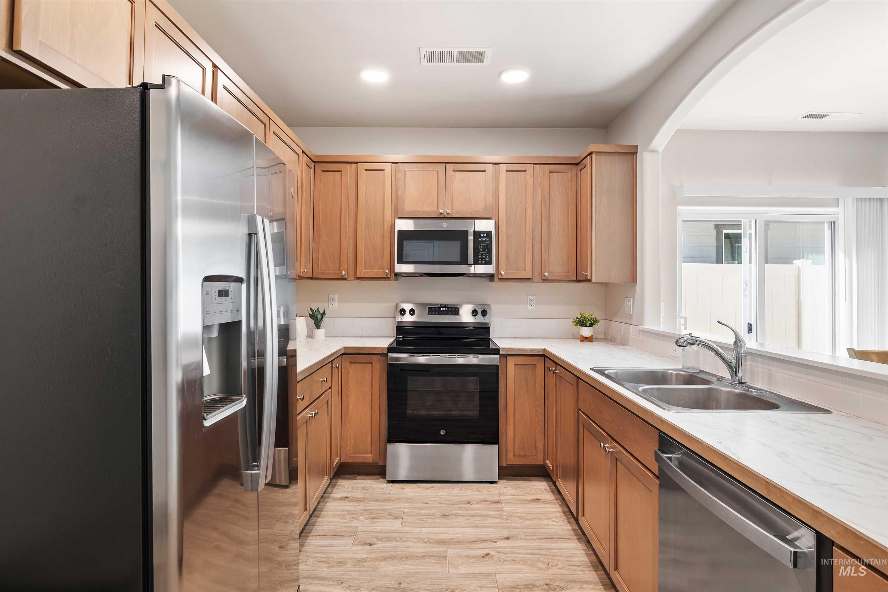 1603 Kenyon Mdw Street Twin Falls, ID 83301 - Photo 9 of 34 Kitchen featuring stainless steel appliances, light countertops, light wood-style floors, recessed lighting, and arched walkways