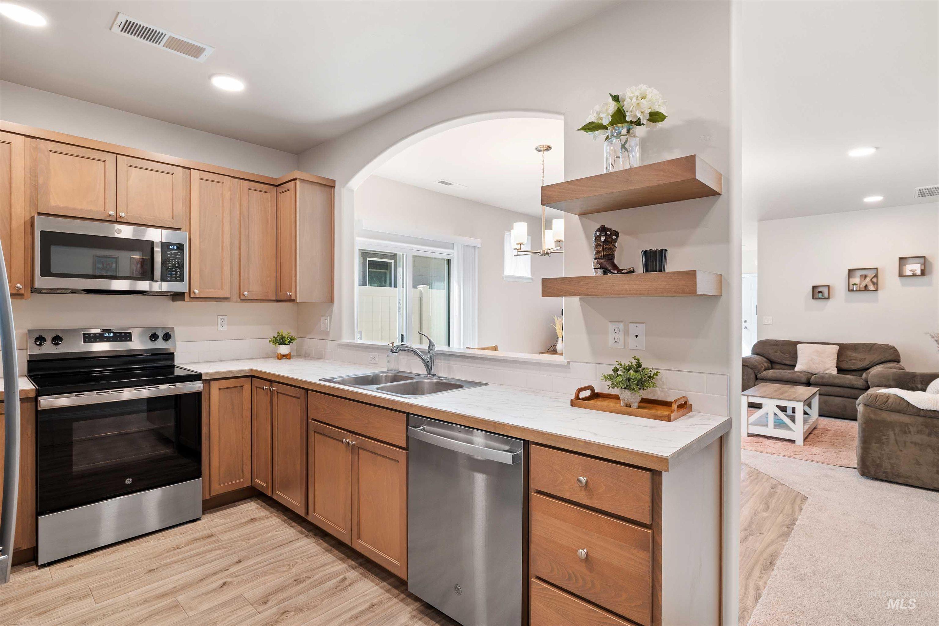 1603 Kenyon Mdw Street Twin Falls, ID 83301 - Photo 31 of 34 Kitchen with stainless steel appliances, light countertops, open floor plan, open shelves, and light wood finished floors