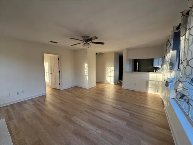 a view of an empty room with a window and wooden floor
