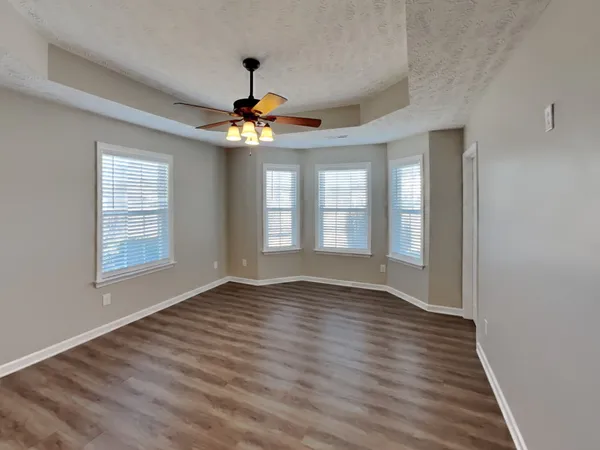 a view of an empty room with chandelier and wooden floor