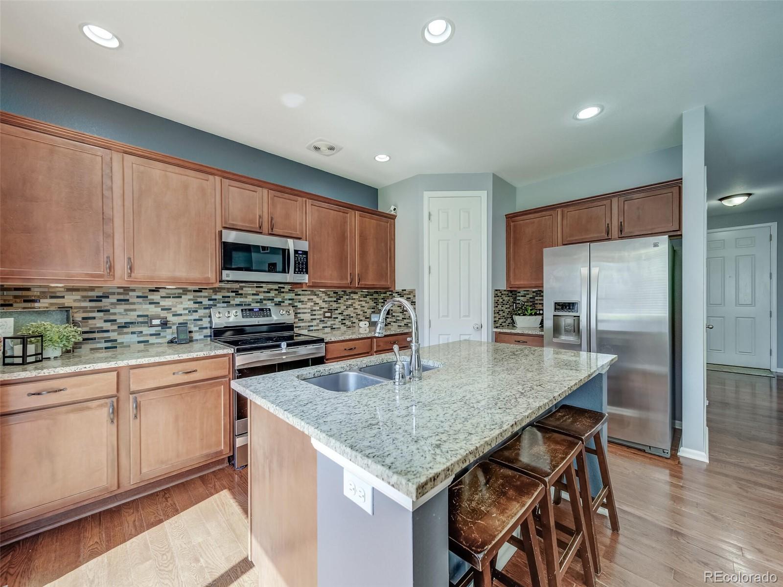 a kitchen with stainless steel appliances granite countertop a kitchen island hardwood floor sink stove and microwave