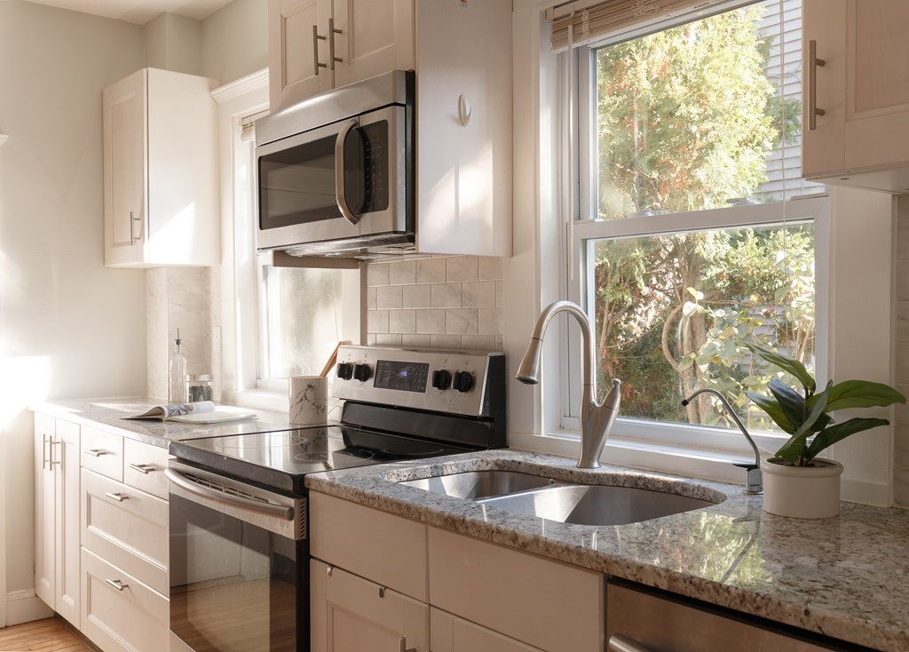 19 Riverside Street Needham, MA 02494 - Photo 6 of 18 a kitchen with granite countertop a sink stainless steel appliances and a window