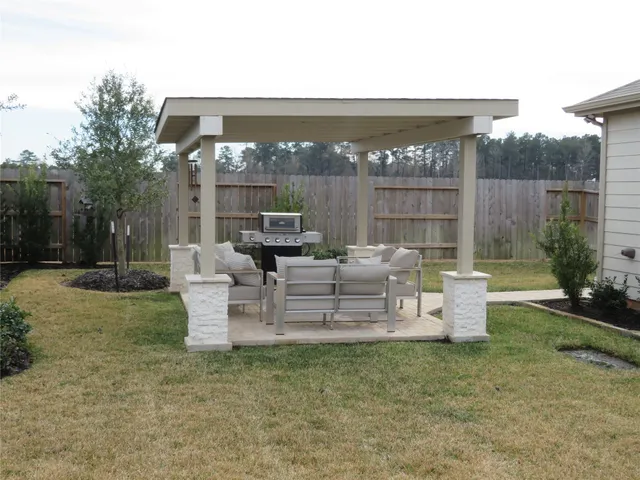 a view of a patio with couches potted plants and wooden fence