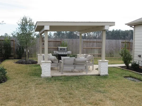 a view of a patio with couches potted plants and wooden fence