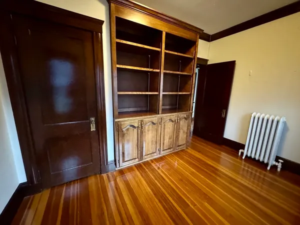 a view of an empty room with wooden floor and a cabinet