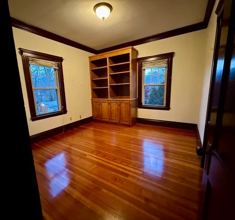 a view of an empty room with wooden floor and windows