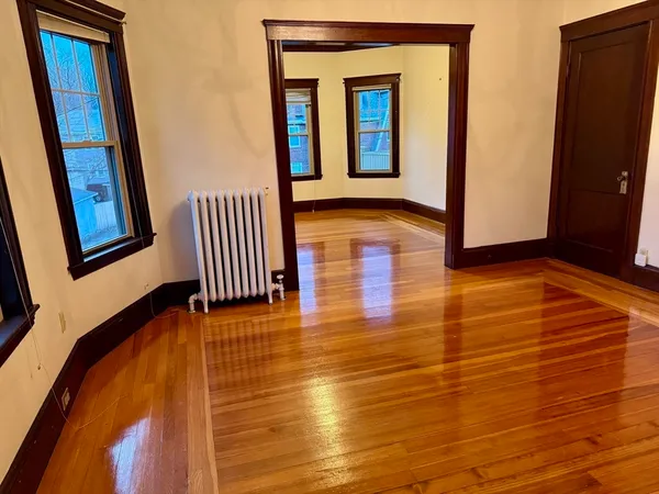 a view of an empty room with wooden floor and a window