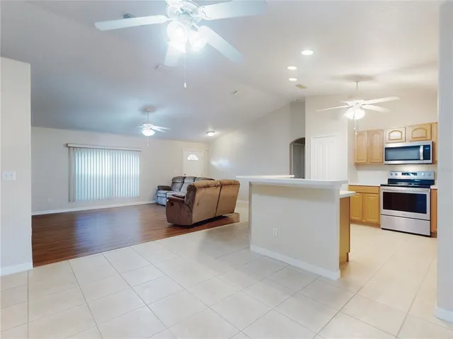 an empty room with a chandelier fan and windows