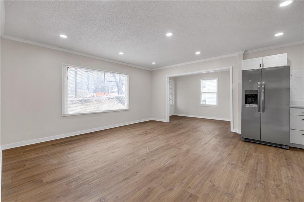 2060 Baker Road Northwest Atlanta, GA 30318 - Photo 5 of 24 an empty room with wooden floor kitchen view and windows