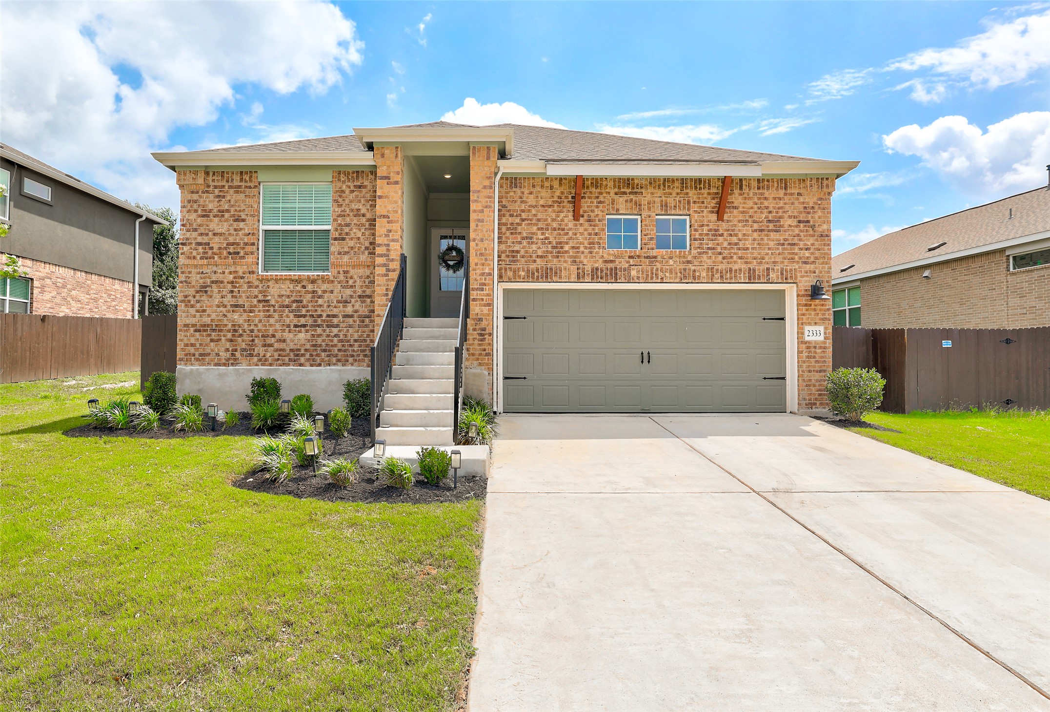 2333 Four Waters Loop Georgetown, TX 78628 - Photo 1 of 35 Brick facade residential property featuring a covered entry, an attached two-car garage, established front landscaping, and a concrete driveway