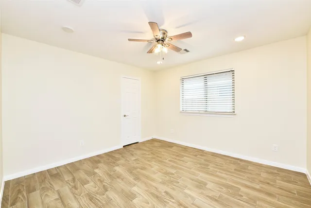 a view of a room with a ceiling fan and wooden floor