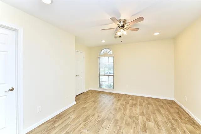 a view of empty room with wooden floor and fan