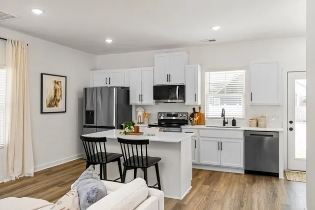 a kitchen with stainless steel appliances a dining table chairs microwave and sink