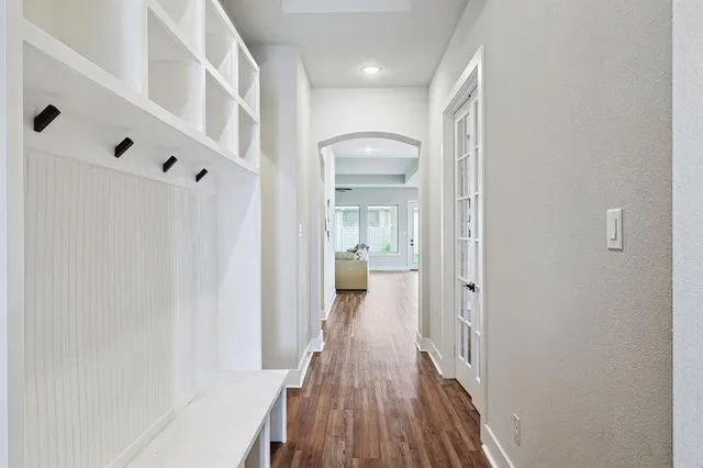 a view of a hallway with wooden floor and a bathroom