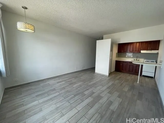 a view of kitchen and empty room with wooden floor