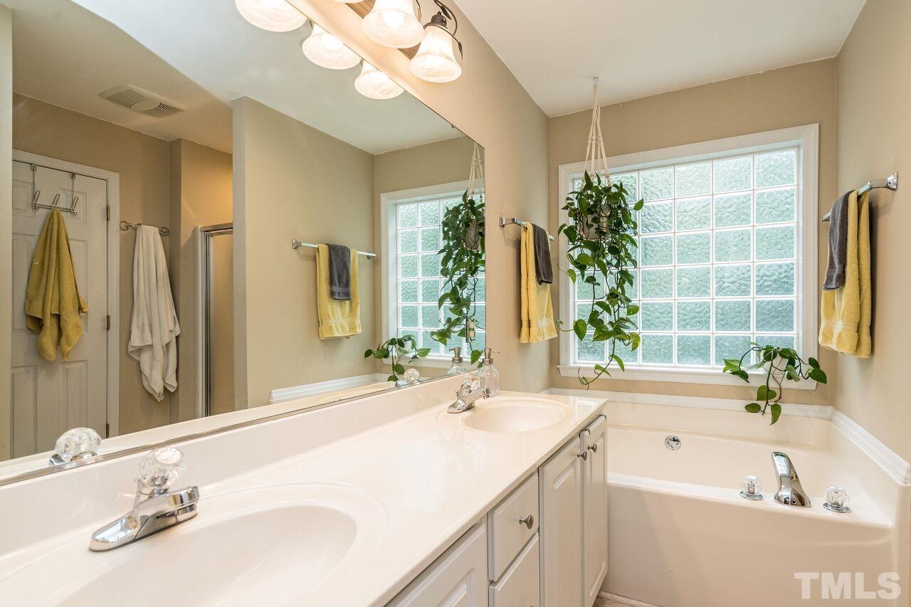 1037 Red Brick Road Garner, NC 27529 - Photo 17 of 33 a bathroom with a granite countertop sink a large mirror and a bathtub next to a window