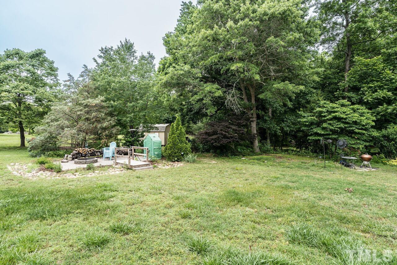 1037 Red Brick Road Garner, NC 27529 - Photo 25 of 33 a view of a backyard with table and chairs and potted plants and large trees