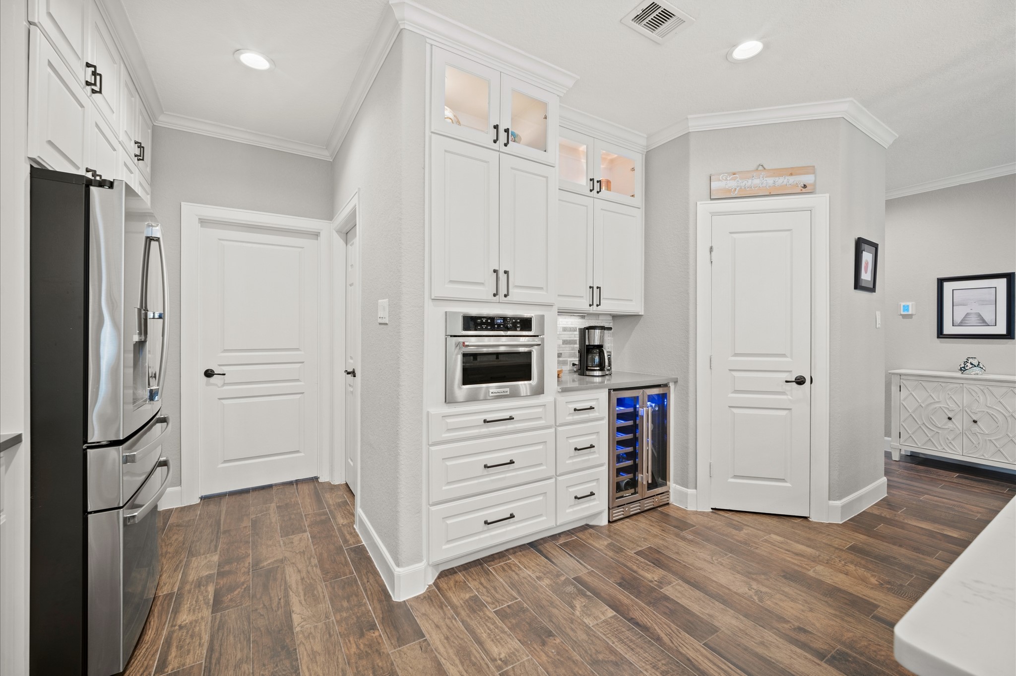 9507 Empress Crossing Drive Spring, TX 77379 - Photo 11 of 50 This kitchen features modern stainless steel appliances, sleek white cabinetry, and wood-style flooring. It includes a built-in microwave, wine cooler, and ample storage space, creating a clean and functional layout.