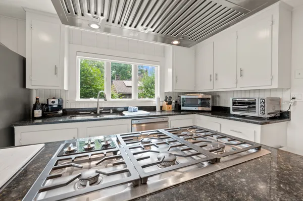 a kitchen with stainless steel appliances granite countertop a stove a sink dishwasher and cabinets with wooden floor