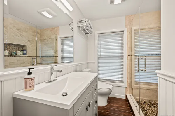 a bathroom with a sink a toilet a mirror and shower