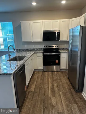 a kitchen with granite countertop a sink stove and refrigerator