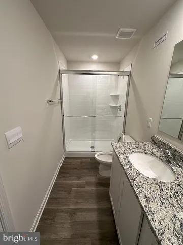 a bathroom with a granite countertop sink a mirror and shower