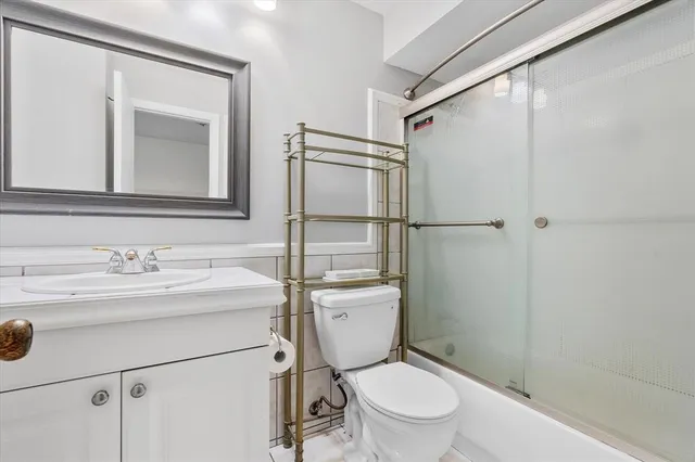 a bathroom with a granite countertop toilet sink vanity and mirror