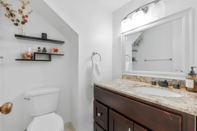 a bathroom with a granite countertop sink a toilet and a mirror