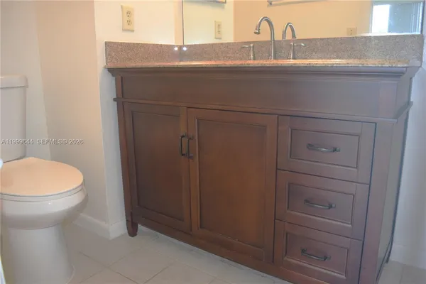 a bathroom with a granite countertop sink and a toilet