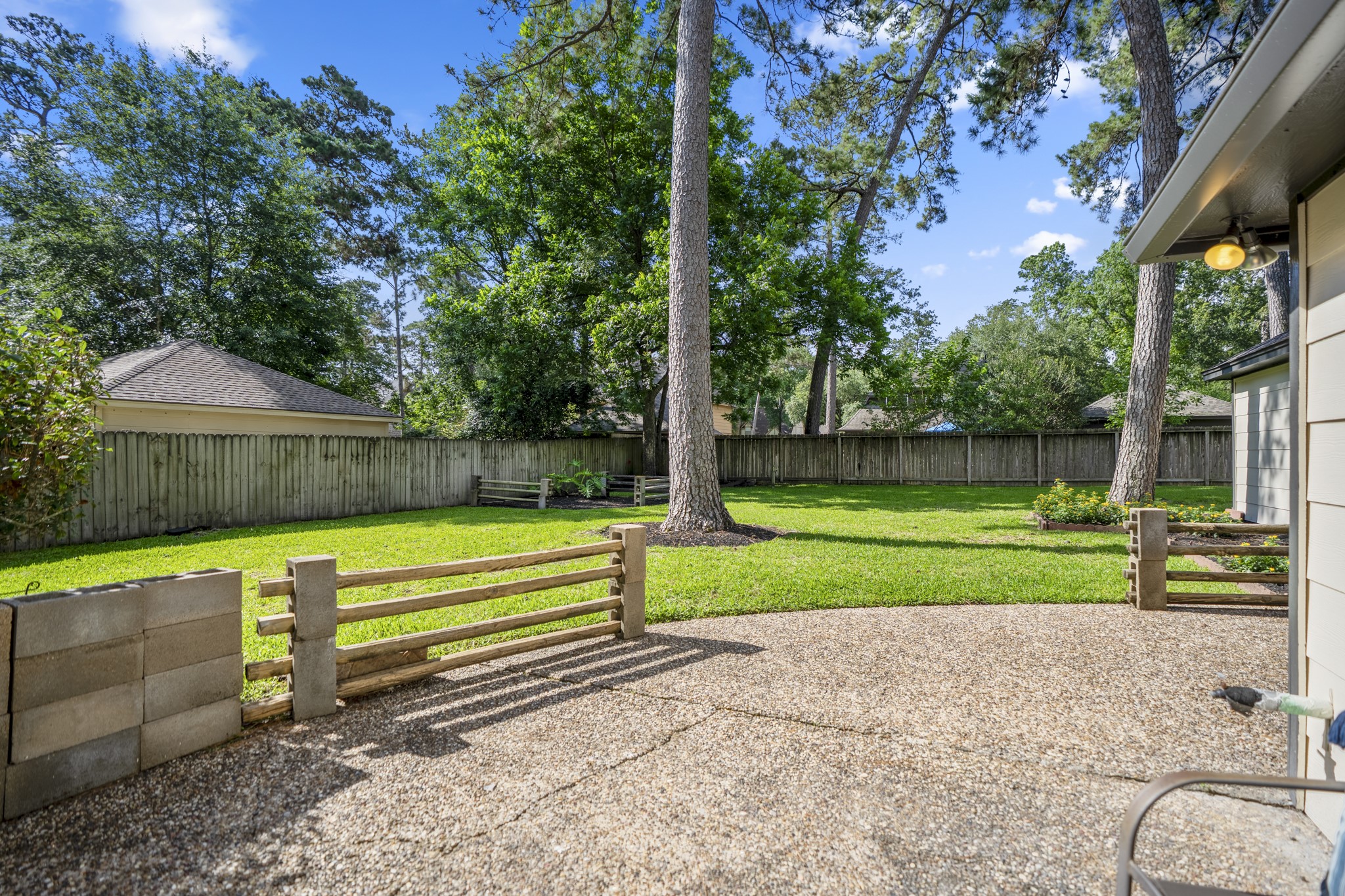 6303 Larkmount Drive Spring, TX 77389 - Photo 40 of 50 Moving outside, the backyard opens up with mature trees, a spacious patio area, and plenty of green space to enjoy. The detached garage sits nearby, while refreshed exterior siding and updated outdoor lighting help carry the home’s improvements beyond the interior.