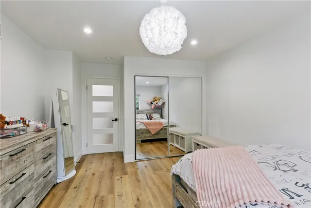 a spacious bedroom with a bed a mirror and lamp on desk