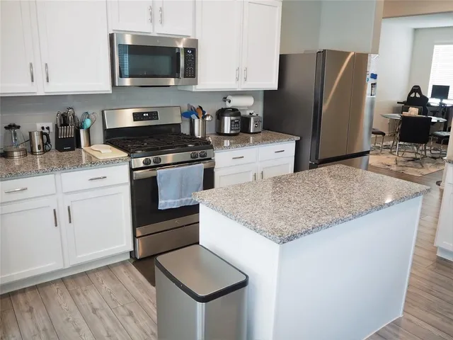 a kitchen with stainless steel appliances granite countertop a refrigerator stove and microwave