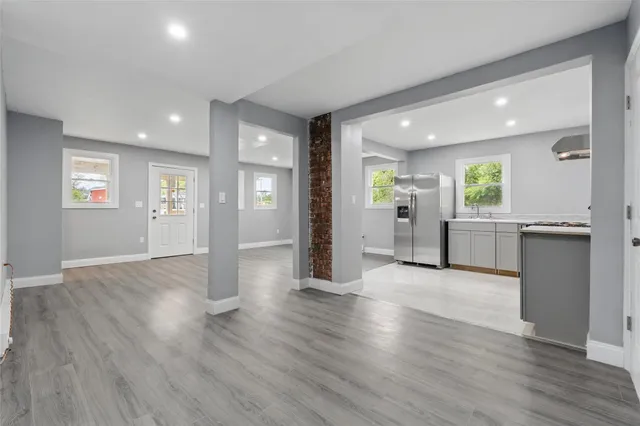 an empty room with wooden floor and windows