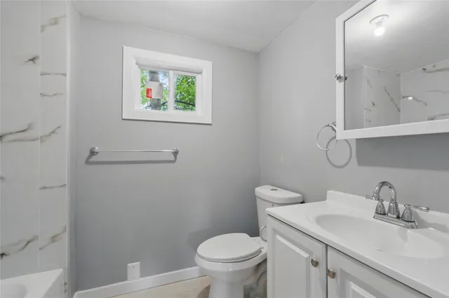 a bathroom with a granite countertop toilet a sink and mirror