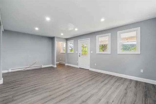 a view of an empty room with wooden floor and windows