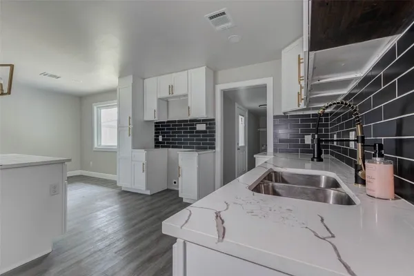 a kitchen that has a sink and a stove with wooden floor