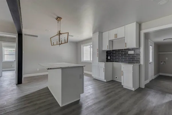 a kitchen with white cabinets and wooden floor
