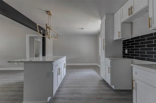 a kitchen with cabinets and wooden floor