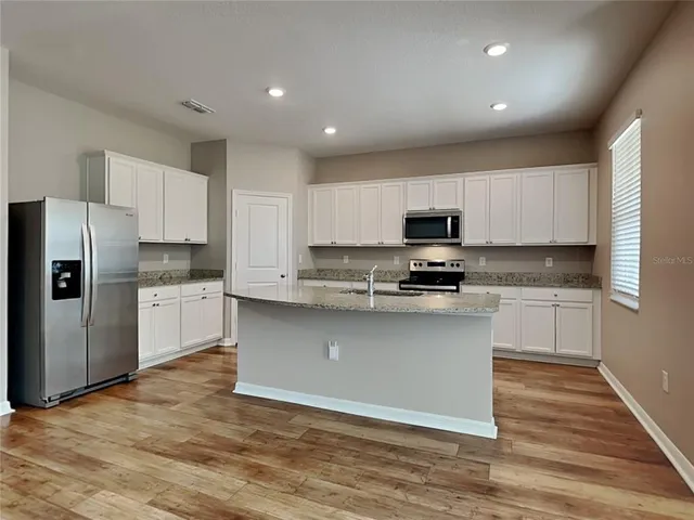 a kitchen with granite countertop white cabinets and stainless steel appliances