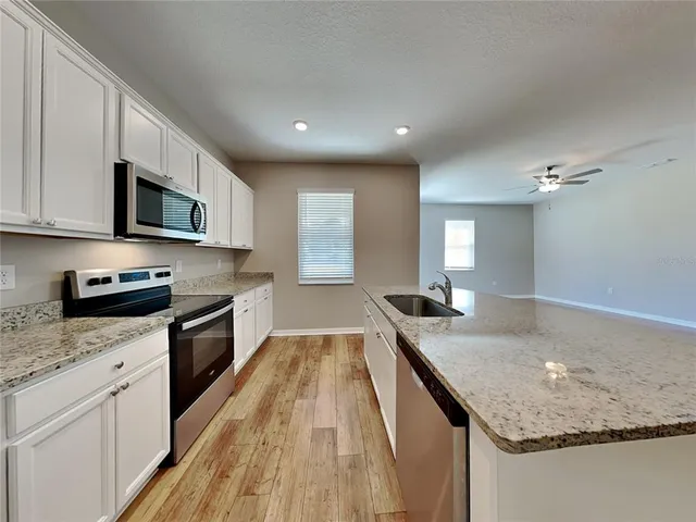 a kitchen with granite countertop stainless steel appliances sink stove microwave and cabinets