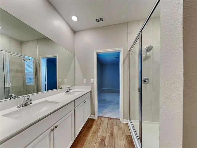 a bathroom with a double vanity sink and mirror with shower