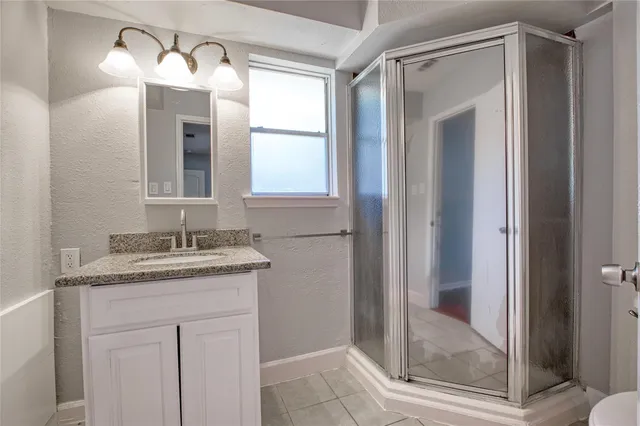 a bathroom with a granite countertop sink a mirror and a shower