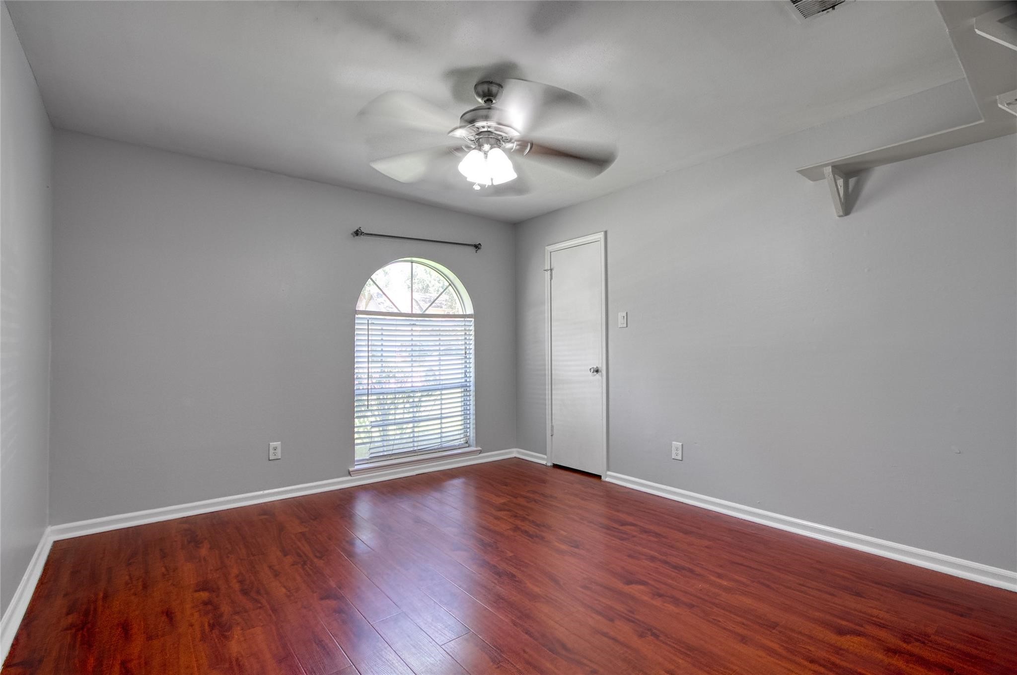 9715 Ballin David Drive Spring, TX 77379 - Photo 17 of 20 an empty room with wooden floor chandelier fan and windows