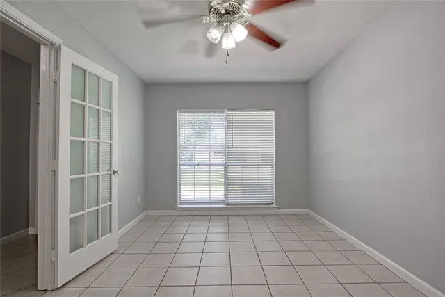 a view of an empty room with window and chandelier fan