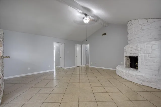 an empty room with fireplace and chandelier fan