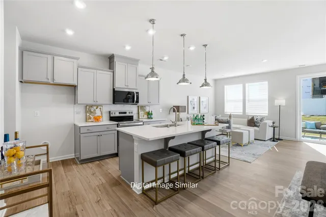 a open kitchen with stainless steel appliances granite countertop a stove a sink dishwasher and a dining table with wooden floor