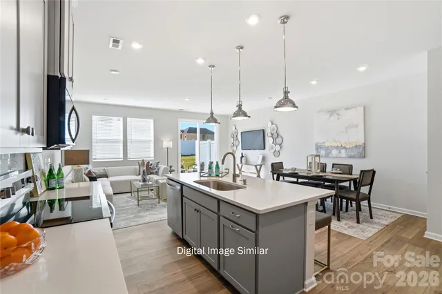 a room with stainless steel appliances kitchen island granite countertop a sink a counter top space and a view of living room