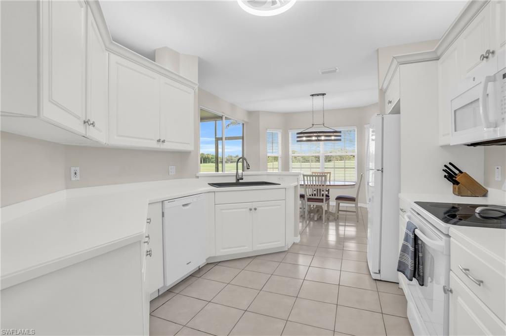 6025 Pinnacle Lane, Unit 602 Naples, FL 34110 - Photo 12 of 43 a kitchen with white cabinets and white appliances